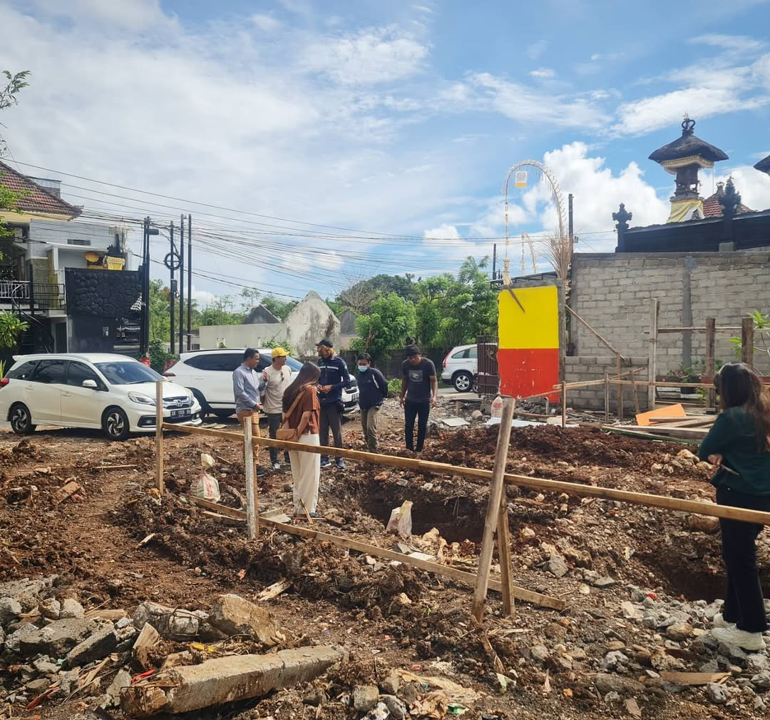 Excavated construction site with parked cars and people