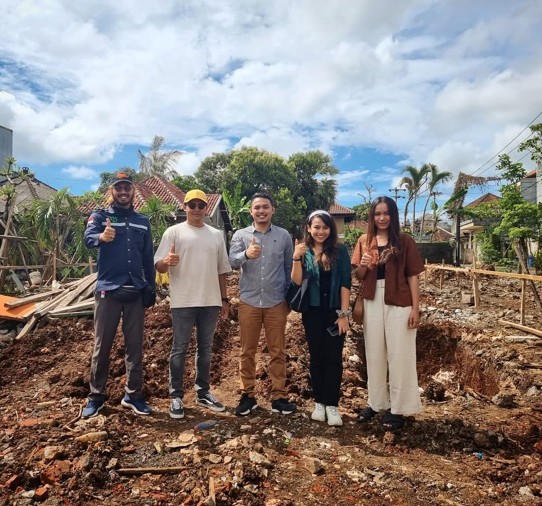 Five people standing on a dirt construction site